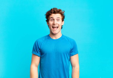 Genç sporcu çocuk mutlu ve hoş bir şekilde şaşırmış görünüyor. Büyülenmiş ve şok olmuş bir ifadeyle heyecanlanıyor.