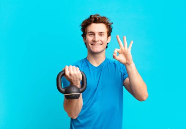 Genç sporcu çocuk kendini mutlu, rahat ve tatmin olmuş hissediyor, iyi bir jestle onaylıyor, gülümsüyor. dambıl konsepti