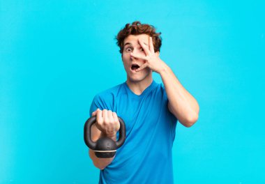 Genç sporcu çocuk şok olmuş, korkmuş ya da korkmuş görünüyordu. Yüzü elle kaplıydı ve parmaklarının arasından bakıyordu. dambıl konsepti