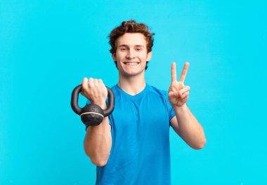 Genç sporcu çocuk gülümsüyor ve arkadaş canlısı görünüyor, iki ya da iki numarayı gösteriyor, eli önde, geriye doğru sayıyor. dambıl konsepti