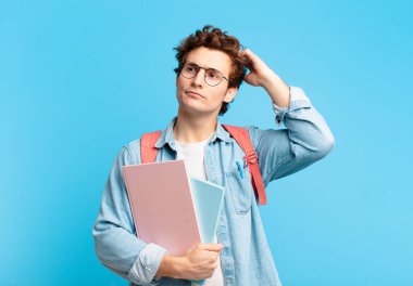 Genç öğrenci şaşkın ve kafası karışmış hissediyor, başını kaşıyor ve yan tarafa bakıyor.