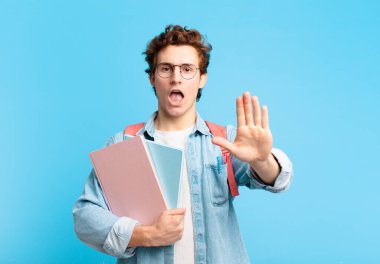 Genç öğrenci ciddi, sert, hoşnutsuz ve kızgın görünüyor. Avuç içini açıp jestleri durduruyor.