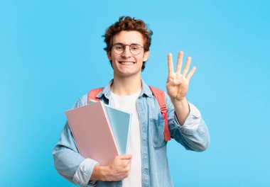 Genç öğrenci gülümsüyor ve arkadaş canlısı görünüyor. Dört ya da dört numarayı gösteriyor. Elleri önde ve geri sayıyor.