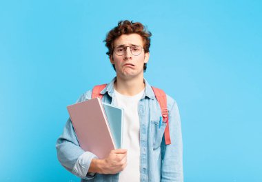 Genç öğrenci üzgün ve mızmız görünüyor. Mutsuz görünüyor. Olumsuz ve hayal kırıklığına uğramış bir tavırla ağlıyor.