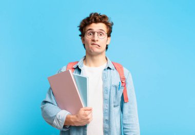 Genç öğrenci şaşkın ve kafası karışmış görünüyor. Sinirli bir hareketle dudağını ısırıyor. Sorunun cevabını bilmiyor.