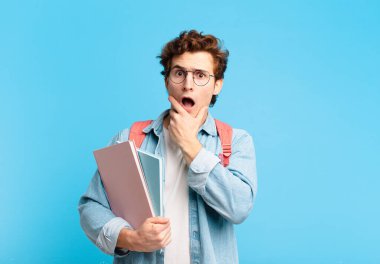 Genç bir öğrenci ağzı ve gözleri açık ve elleri çenesinde, nahoş bir şekilde şokta, ne söylüyor ya da vay canına