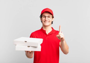 Pizza dağıtan çocuk gülümsüyor ve arkadaş canlısı görünüyor. Bir numarayı gösteriyor ya da ilk eli önde, geri sayıyor.