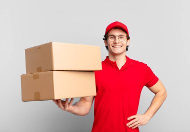 Paketçi çocuk mutlu bir şekilde gülümsüyor. Kendine güvenen, olumlu, gururlu ve arkadaş canlısı bir tavırla.