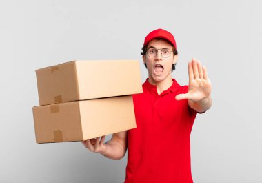 Paket teslimatçısı çocuk ciddi, sert, hoşnutsuz ve kızgın görünüyor.