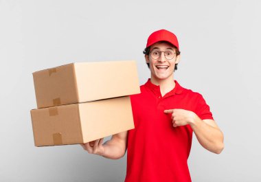 Paket teslimatçı çocuk mutlu, şaşkın ve gururlu, heyecanlı ve şaşkın bir bakışla kendini işaret ediyor.