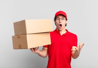 Paket teslimatçısı çocuk ağzı açık ve şaşırmış, şok olmuş ve hayrete düşmüş inanılmaz bir sürprizle