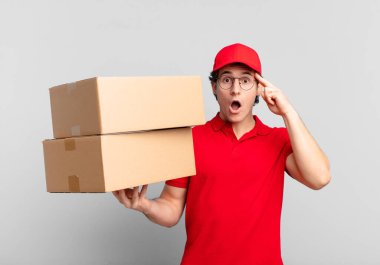 Paketçi çocuk şaşırmış, ağzı açık, şok olmuş, yeni bir düşünce, fikir ya da konsept keşfediyor.