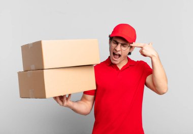 Paket teslimatçısı mutsuz ve stresli görünüyor, intihar jesti elle silah işareti yapıyor, kafasını işaret ediyor.