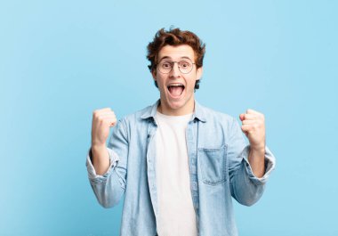 Genç yakışıklı çocuk şokta, heyecanlı ve mutlu, gülüyor ve başarıyı kutluyor,!