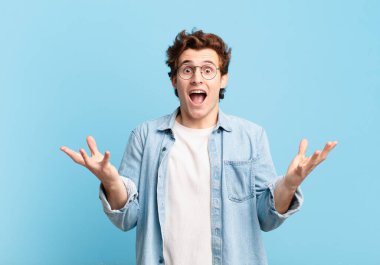 Genç yakışıklı çocuk mutlu, heyecanlı, şaşırmış ya da şok olmuş hissediyor, gülümsüyor ve hayrete düşüyor.