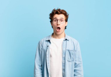 Genç yakışıklı çocuk şok olmuş ya da şaşırmış görünüyor, ağzı açık bir şekilde 