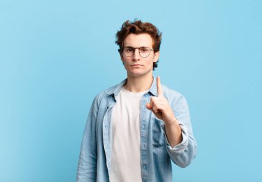 Genç yakışıklı çocuk kızgın, sinirli, isyankar ve agresif orta parmağını sallayarak karşılık veriyor.