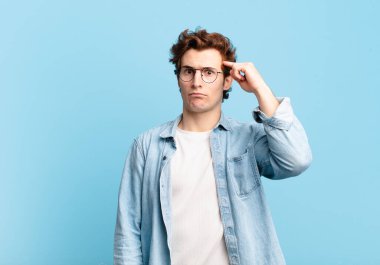 Genç yakışıklı çocuk şaşkın ve şaşkın hissediyor, deli, deli ya da aklını kaçırmış olduğunu gösteriyor.