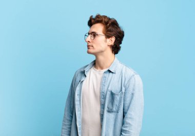 Profil görünümünde genç yakışıklı çocuk ilerideki boşluğu kopyalamaya çalışıyor, düşünüyor, hayal ediyor ya da hayal kuruyor.