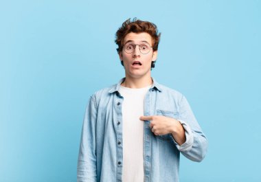 Şok olmuş ve ağzı açık, kendini işaret eden genç ve yakışıklı bir çocuk.