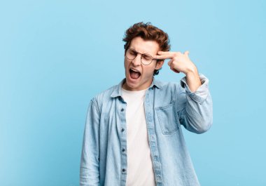 Genç yakışıklı çocuk mutsuz ve stresli görünüyor, intihar jesti silahla işaret ediyor, kafasını işaret ediyor.