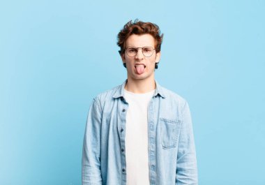 Genç yakışıklı çocuk tiksinmiş ve rahatsız olmuş hissediyor, dilini dışarı çıkarıyor, iğrenç ve iğrenç bir şeyden hoşlanmıyor.