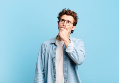 Genç yakışıklı çocuk düşünüyor, kuşkulu ve şaşkın hissediyor, farklı seçeneklerle, hangi kararı vereceğini merak ediyor.