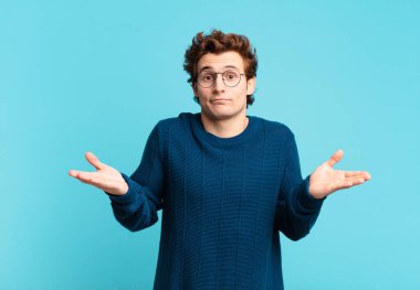 Genç yakışıklı çocuk şaşkın ve şaşkın, şüpheci, farklı seçenekleri tartıyor ya da komik bir ifadeyle seçiyor.
