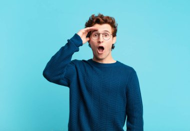 Genç yakışıklı çocuk mutlu, şaşkın ve şaşırmış görünüyor, gülümsüyor ve inanılmaz ve inanılmaz iyi haberleri fark ediyor.