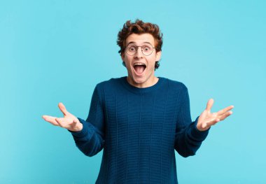 Genç yakışıklı çocuk mutlu, heyecanlı, şaşırmış ya da şok olmuş hissediyor, gülümsüyor ve hayrete düşüyor.