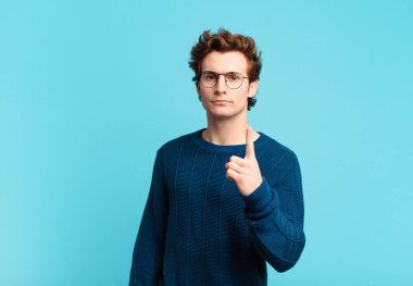 Genç yakışıklı çocuk kızgın, sinirli, isyankar ve agresif orta parmağını sallayarak karşılık veriyor.