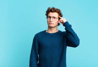 Genç yakışıklı çocuk şaşkın ve şaşkın hissediyor, deli, deli ya da aklını kaçırmış olduğunu gösteriyor.