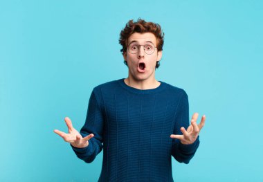 Genç, yakışıklı, ağzı açık ve şaşkın, şok olmuş ve hayrete düşmüş bir çocuk.