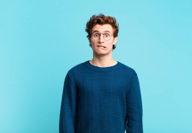 Genç yakışıklı çocuk şaşkın ve şaşkın görünüyor, gergin bir hareketle dudağını ısırıyor, sorunun cevabını bilmiyor.