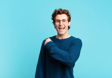 Genç yakışıklı çocuk mutlu, pozitif ve başarılı hissediyor, bir meydan okumayla karşılaştığında motive oluyor veya iyi sonuçları kutluyor.