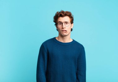 young handsome boy feeling puzzled and confused, with a dumb, stunned expression looking at something unexpected