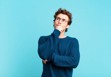 Genç yakışıklı çocuk düşünüyor, kuşkulu ve şaşkın hissediyor, farklı seçeneklerle, hangi kararı vereceğini merak ediyor.