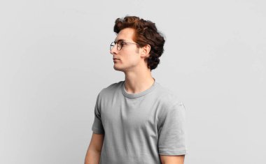 Profil görünümünde genç yakışıklı çocuk ilerideki boşluğu kopyalamaya çalışıyor, düşünüyor, hayal ediyor ya da hayal kuruyor.