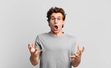 Genç yakışıklı çocuk şok olmuş ve şaşırmış, endişeli ve paniklemiş, stresli ve korkmuş bir bakışla