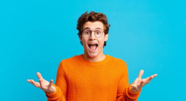 Genç yakışıklı çocuk mutlu, heyecanlı, şaşırmış ya da şok olmuş hissediyor, gülümsüyor ve hayrete düşüyor.