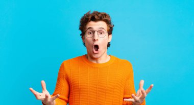 Genç, yakışıklı, ağzı açık ve şaşkın, şok olmuş ve hayrete düşmüş bir çocuk.