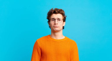 Genç yakışıklı çocuk üzgün ve mızmız, mutsuz bir bakışla, negatif ve hayal kırıklığına uğramış bir tavırla ağlıyor.