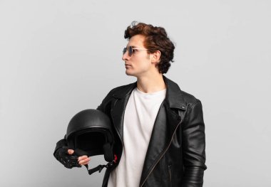 Motosikletli çocuk profil görünümünde. İleriyi kopyalamak istiyor. Düşünüyor, hayal ediyor ya da hayal kuruyor.