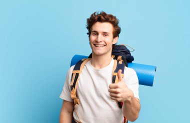 Yürüyüşçü çocuk gururlu, tasasız, kendinden emin ve mutlu, başparmağıyla olumlu gülümsüyor.