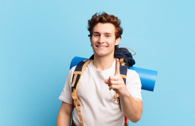 Yürüyüşçü çocuk gururla gülümsüyor ve gururla bir numaralı pozunu veriyor, kendini lider gibi hissediyor.