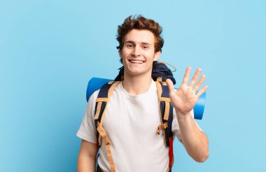 Yürüyüşçü çocuk mutlu ve mutlu bir şekilde gülümsüyor, el sallıyor, seni selamlıyor ve selamlıyor, ya da veda ediyor.