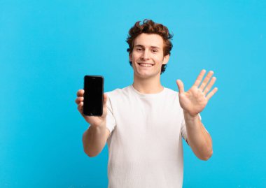 Genç çocuk mutlu ve neşeyle gülümsüyor, el sallıyor, seni selamlıyor ve selamlıyor, ya da hoşça kal diyor. telefon ekranı kavramı