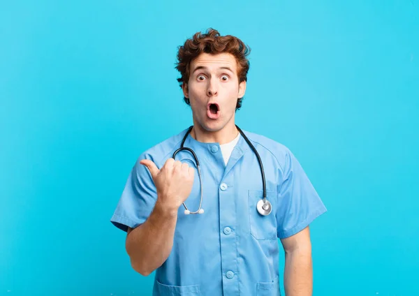 Young Nurse Man Looking Astonished Disbelief Pointing Object Side Saying — Stock Photo, Image