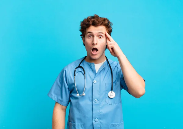 Joven Enfermero Mirando Sorprendido Con Boca Abierta Sorprendido Realizando Nuevo —  Fotos de Stock