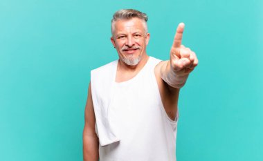 Kıdemli sporcu gülümsüyor ve arkadaş canlısı görünüyor. Bir numara ya da ilk eli önde, geriye doğru sayıyor.